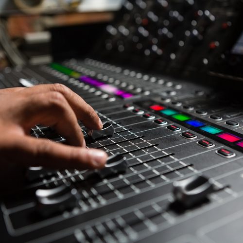 Hand of male audio engineer using sound mixer in recording studio